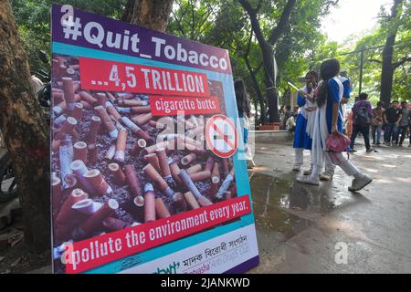 Dhaka. 31st maggio 2022. La gente è vista accanto a un manifesto di sensibilizzazione contro il tabacco durante la Giornata mondiale contro il tabacco a Dhaka, Bangladesh, il 31 maggio 2022. La Giornata mondiale del tabacco è celebrata ogni anno il 31 maggio. Il tema di quest'anno "tabacco: Minaccia per il nostro ambiente” offre alle persone un motivo in più per smettere di fumare dimostrando l'impatto ambientale del tabacco. Credit: Xinhua/Alamy Live News Foto Stock