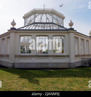 Richmond, Greater London, Inghilterra, maggio 18 2022: Royal Botanic Gardens Kew. Casa temperata come un aereo vola in alto. Foto Stock