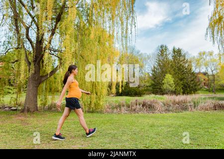 Allenamento prenatale donna incinta che cammina fuori nel parco vivendo uno stile di vita attivo durante la gravidanza. Passeggiate giornaliere durante l'estate all'aperto Foto Stock