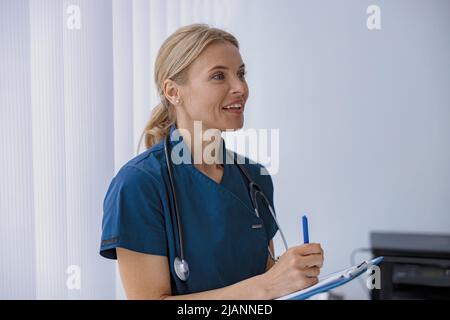 Il medico compila il modulo di rapporto medico sulle cure mediche dei pazienti durante l'appuntamento Foto Stock