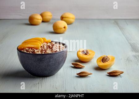 Colazione energetica. Fiocchi d'avena a grani interi con semi di lino e fette di albicocca su tavolo di legno blu dipinto Foto Stock