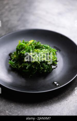 Insalata di alghe in piatto nero Foto Stock