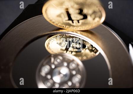 Bitcoin che si riflette sul disco rigido. Medaglia di cripto in oro su hardware. Concetto di criptovaluta mineraria Foto Stock