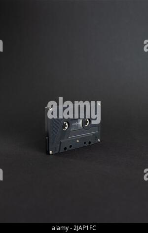 Primo piano della cassetta audio, isolata su sfondo grigio scuro. Nastro audio analogico. Audio K7 nastro isolato e centrale su sfondo scuro Foto Stock