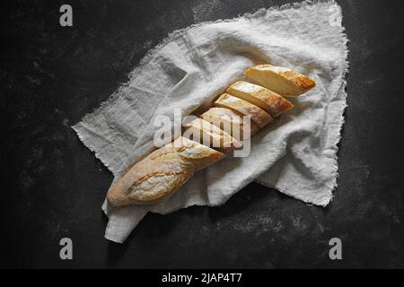 Baguette fresche croccanti su tovagliolo di lino sul tavolo nero. Vista dall'alto. Foto Stock