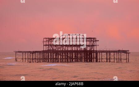 Resti arrugginiti del deprepit West Pier contro un cielo rosa crepuscolo. Brighton & Hove, Sussex, Inghilterra, Regno Unito. Foto Stock