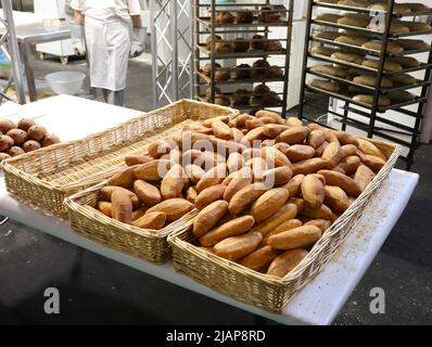 panetteria industriale per la produzione di pane e baguette appena sfornate in cestini di vimini pronti per la vendita da parte del panettiere Foto Stock