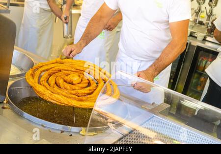 Un uomo che fa churros in un bar Foto Stock