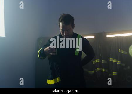 Giovane vigile del fuoco afroamericano di notte in una stazione dei vigili del fuoco. Foto Stock