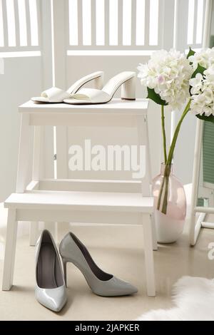 Scala a gradini con eleganti scarpe femminili e bellissimi fiori in camera Foto Stock