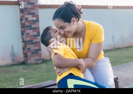 mamma bacia suo figlio nel parco molto felice Foto Stock