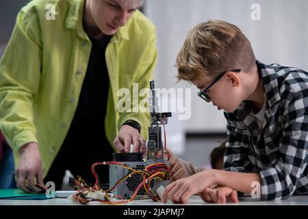 Studente con insegnante che lavora insieme al progetto con giocattoli elettrici e robot in classe robotica Foto Stock