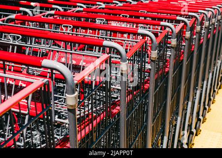 Primo piano di carrelli in metallo per supermercati con maniglie rosse sulla strada Foto Stock