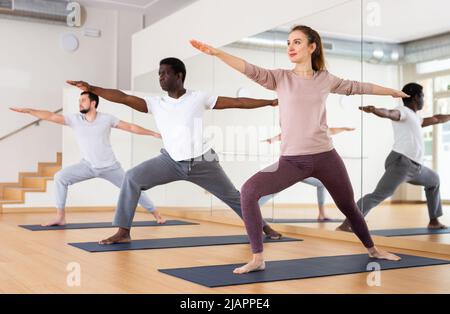 Donna in piedi in affondo asana Virabhadrasana in studio yoga Foto Stock