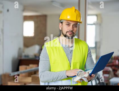 Architetto bearded con laptop in piedi in casa sotto la ricostruzione Foto Stock