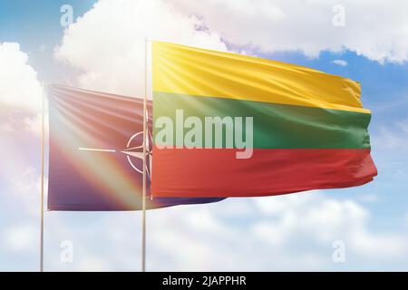 Cielo azzurro soleggiato e bandiere della lituania e della nato Foto Stock