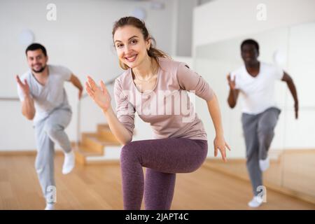 Donna danza aerobica con gli uomini in studio Foto Stock