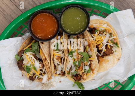 Vista dall'alto della varietà di tacos, tra cui pollo, bistecche e maiale, serviti in un cestino di fast food. Foto Stock