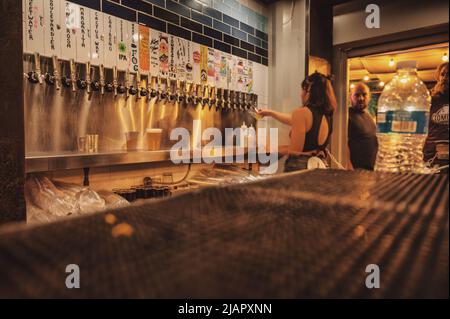 Il barista versa la birra nella birreria di Tucson al mercato notturno estivo. Sfocatura intenzionale della fotocamera dovuta a un'esposizione prolungata Foto Stock