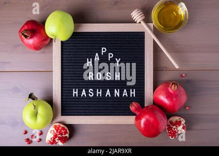 Iscrizione con congratulazioni a Rosh Hashanah, melagrane tradizionali, mele verdi e miele. Capodanno ebraico. Congratulazioni. Focu selettivo Foto Stock