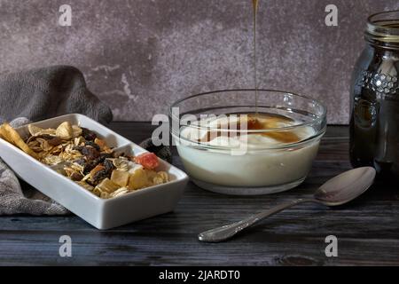 Vaso di miele naturale e yogurt fatto in casa accanto a un contenitore di noci Foto Stock