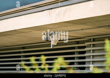 Telecamera di sicurezza e rilevatore di movimento posizionati sulla facciata di un edificio Foto Stock