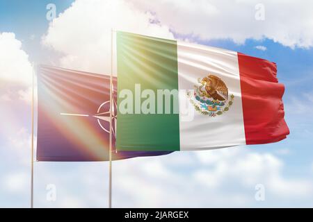 Cielo azzurro soleggiato e bandiere del messico e della nato Foto Stock