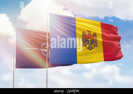 Cielo azzurro soleggiato e bandiere della moldavia e della nato Foto Stock