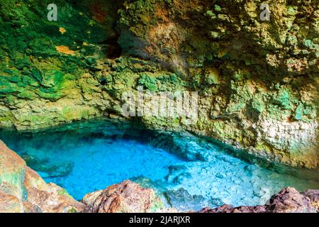 Vista della splendida piscina naturale di acqua cristallina formata in una grotta rocciosa con stalagmiti e stalagmiti. Caverna di Kuza a Zanzibar, Tanzania Foto Stock