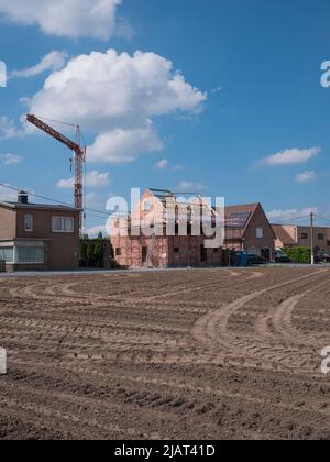 Sint Gillis WAAS, Belgio, 29 maggio 2022, casa in costruzione con un ponteggio intorno ad esso, cielo blu con nuvole bianche e in primo piano una frana Foto Stock