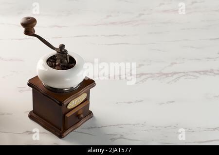 An antique coffee grinder on a marble pattern. The word "coffee" contained in the object is not a brand name, but is graphic element Foto Stock