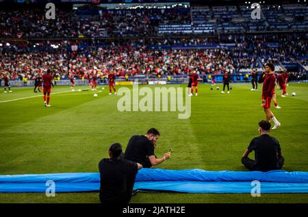 Aufgrund der verspäteten Anstoßzeit sitzen Volontarii für die coreo während der zweiten Aufwärmphase am Spielfeldrand FC Liverpool - Real Madrid Pa Foto Stock