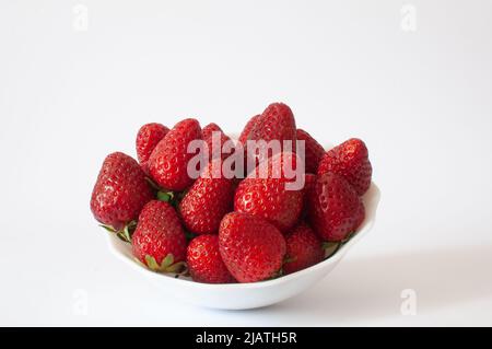 Fragole rosse dolci, vista ad angolo delle bacche succose e dolci in ciotola bianca. Isolato su sfondo bianco, fuoco selettivo. Foto Stock