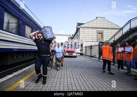 Un volontario porta un sacco di una donna anziana che sta per essere evacuata in treno a Dnipro. Pokrovske è una piccola città situata nella regione di Donetsk.IT è la città principale per evacuare civili a Dnipro in treno, ogni giorno centinaia di civili evacuati dalle zone di conflitto della regione vengono portati alla stazione ferroviaria da volontari che li aiutano a salire in treno e a spostarsi in aree più sicure del paese. Molti di loro sono anziani provenienti da piccoli villaggi situati nelle zone di combattimento e hanno bisogno di aiuto a causa della loro condizione fragile. Foto Stock