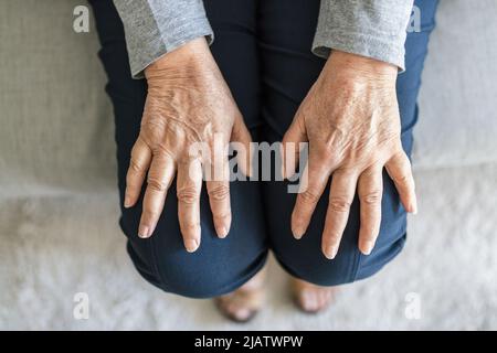 Donna anziana a casa che soffre di artrite Foto Stock