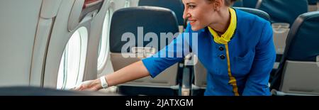 Allegro stewardess guardando fuori la finestra in aereo Foto Stock