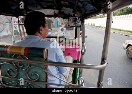 Bangkok, Thailandia - 4 aprile 2011: Una vista dall'interno di un Tuk Tuk sulle strade di Bangkok con conducente maschile e la strada Foto Stock