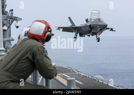 I Marines USA con attacco dei combattenti marini Squadron (VMFA) 121 osservano un F-35B Lightning II atterra a bordo della nave d'assalto anfibio USS Tripoli (LHA 7), mentre era in corso, 24 maggio 2022. Marines con VMFA-121, con sede presso la Marine Corps Air Station Iwakuni, Giappone, stanno conducendo operazioni di volo a sostegno di un libero e aperto Indo-Pacific. (STATI UNITI Foto del corpo marino di Sgt. Jackson Ricker) Foto Stock