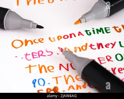 Tre marcatori che posano su un pezzo di carta con una storia che è in una scrittura a mano dei bambini una volta... Foto Stock