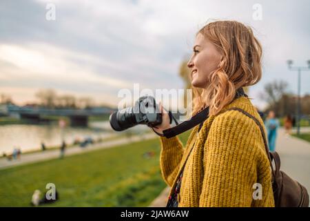 Fotografo viaggiatore 30s donna in stile abiti casual scattare foto con videocamera all'aperto in vista della città. Copia mockup spazio. Hobie concetto di avventura Foto Stock