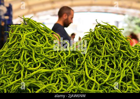 Venditore che vende peperoni verdi sul mercato Foto Stock