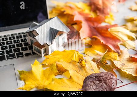 mockup modello casa e lascia vicino computer portatile su un tavolo. Stagione autunnale Foto Stock