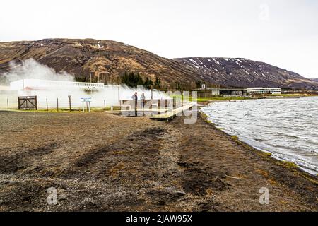 Laugarvatn Fontana. La sorgente termale fornisce calore geotermico a tutto il luogo. Sulla riva il bagno geotermico Laugarvatn Fontana. Sopra un ponte sono i fori caldi nella terra per cuocere Hverabrauð, chiamato anche Rúgbrauð.. Cottura geotermica pane di segale islandese a Laugarvatn Fontana, Islanda Foto Stock