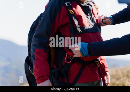 Uomo che aiuta il pilota del parapendio a prepararsi per il volo, primo piano Foto Stock