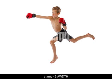 Punzonatura. Ragazzino, ragazzo in sport colpi e guanti che praticano la boxe tailandese su sfondo bianco studio. Sport, educazione, azione, motion concept. Foto Stock