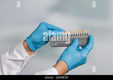 primo piano della mano del dentista che presenta la guida dell'ombra per controllare l'impiallacciatura dei denti Foto Stock