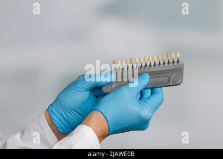 primo piano della mano del dentista che presenta la guida dell'ombra per controllare l'impiallacciatura dei denti Foto Stock