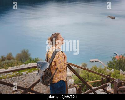 Viaggi e attrazioni turistiche a Kekova isola, Turchia. Donna viaggiatore esplora le rovine del castello di Simena con vista sulla baia del mare e l'isola di Kekova con fa Foto Stock