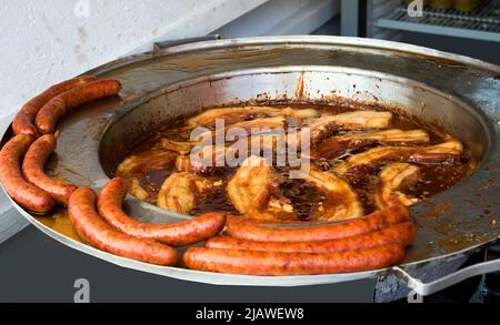 Pancetta alla griglia e salsicce vendute sulla fiera del mercato tradizionale Foto Stock