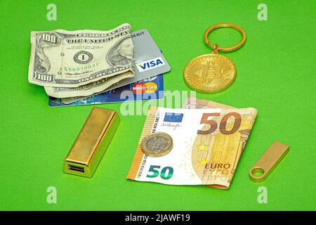 Londra, Regno Unito - 27 maggio 2022: Cripto valuta del bitcoin d'oro con il dollaro della barra d'oro e le fatture della carta dell'euro e delle carte di credito e delle monete come senso di pa Foto Stock